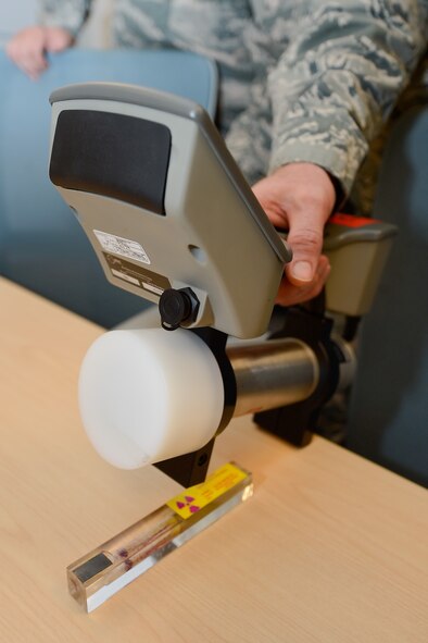 Col. Michael Grismer, 436th Airlift Wing commander, holds a SAM 940 radiation identification machine over a piece of very-low radioactive material enclosed in plastic while learning how sensitive the machine is during a visit to the 436th Aerospace Medicine Squadron Bioenvironmental Flight July 17, 2015, at Dover Air Force Base, Del. Grismer saw first-hand the sensitivity of the equipment and learned how it would be used during his visit. (U.S. Air Force photo/Greg L. Davis)
