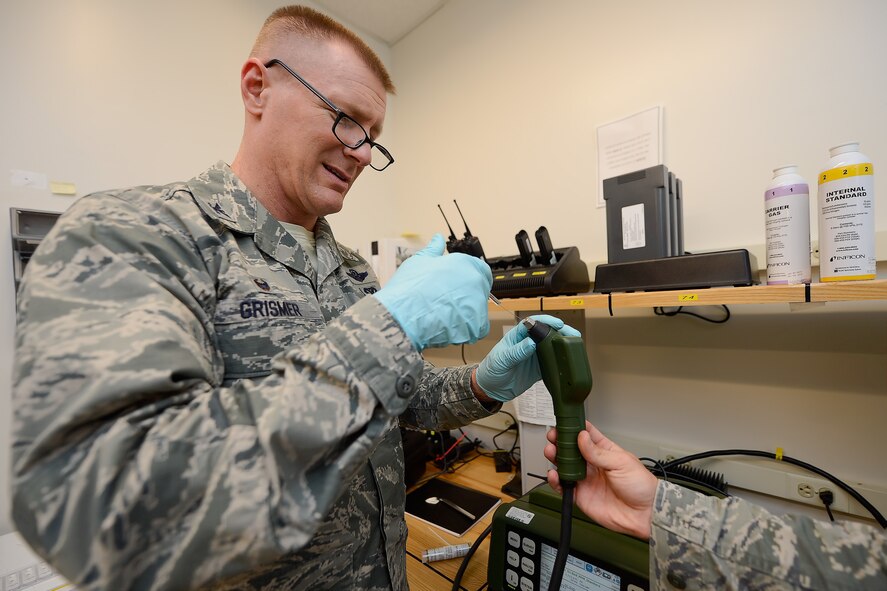 Col. Michael Grismer, 436th Airlift Wing commander, inserts a syringe with fluid to be tested in a device held by Staff Sgt. Jeffry Stamm, 436th Aerospace Medicine Squadron Readiness Flight NCO in charge, during a mission capabilities demonstration July 17, 2015, at Dover Air Force Base, Del. Grismer wears medical gloves as a safety precaution. (U.S. Air Force photo/Greg L. Davis)