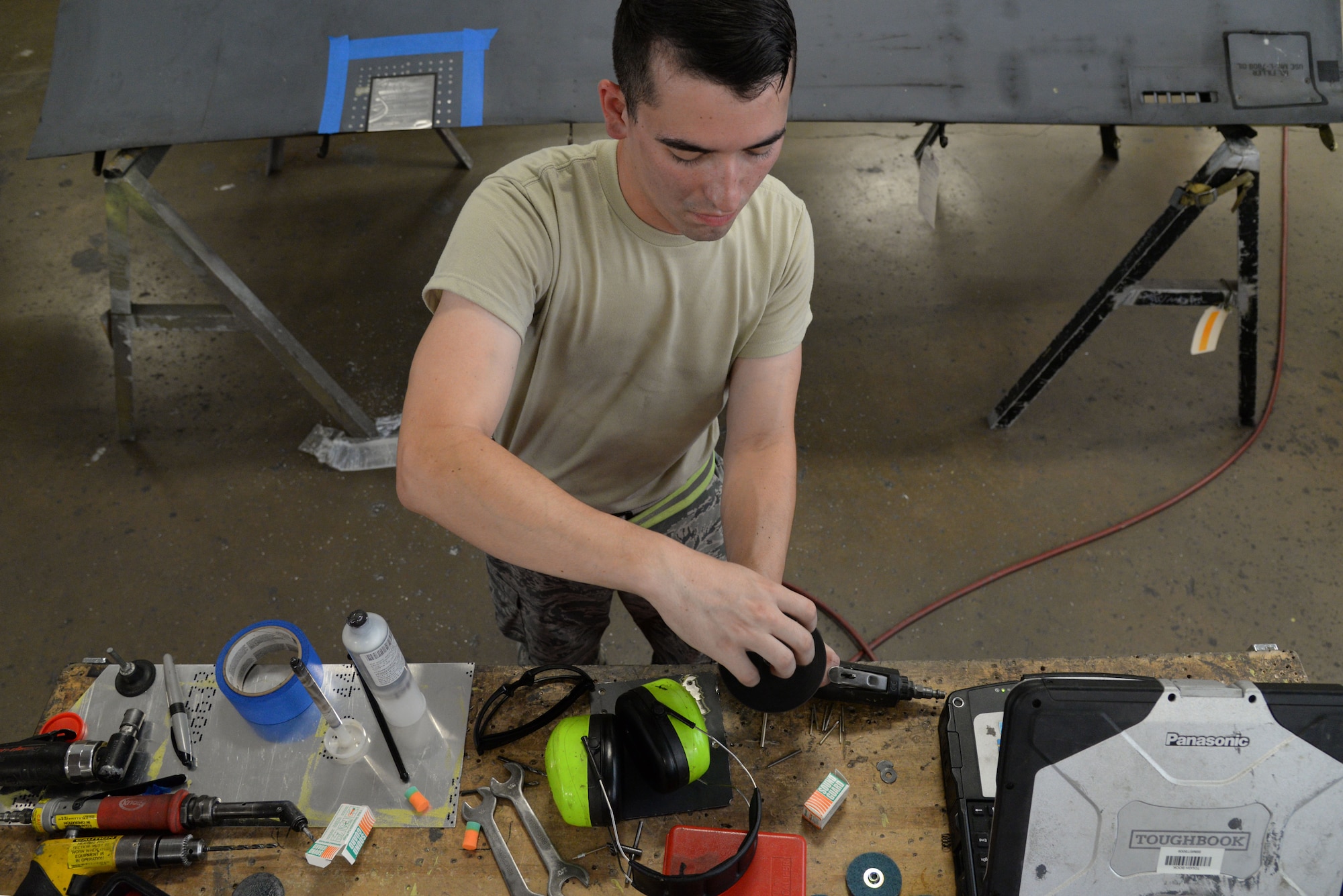 Senior Airman Dylan Fox, 707th Maintenance Squadron aircraft structural maintenance journeyman, puts away a tool while waiting for the sealent to dry on the skin repair on Barksdale Air Force Base, La., July 20, 2015. The sealent is used to seal two separate pieces of metal together. (U.S. Air Force photo/ Senior Airman Jannelle Dickey)