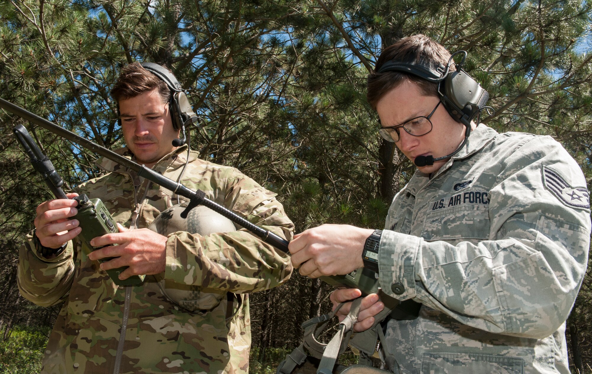 Airman 1st Class William Barron (left), and Staff Sgt. Clarence Rainey, 791st Missile Security Forces Squadron tactical response force members, adjust their radios and headsets near Garrison, N.D., July 20, 2015. Barron and Rainey stood in a wooded area so UH-N1 Helicopter crew members could practice search and rescue procedures. (U.S. Air Force photo/Senior Airman Stephanie Morris)