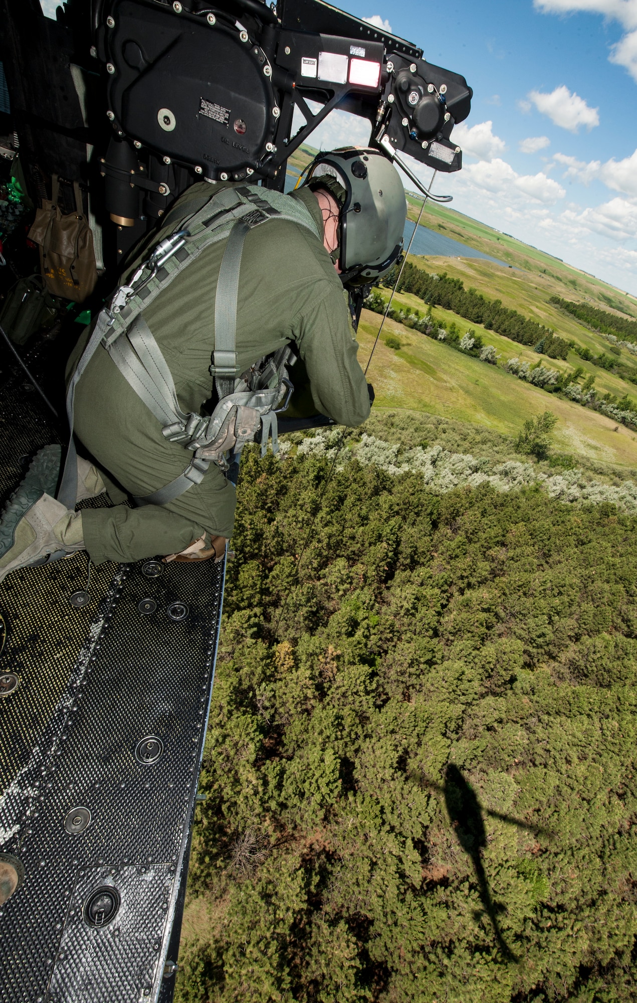 Staff Sgt. Nicholas Estrada, 54th Helicopter Squadron flight engineer, conducts search and rescue training from a UH-N1 Helicopter near Garrison, N.D., July 20, 2015. During the training, Estrada and the helicopter’s crew had to locate and hoist two tactical response force members from a field near a wooded area. (U.S. Air Force photo/Senior Airman Stephanie Morris)