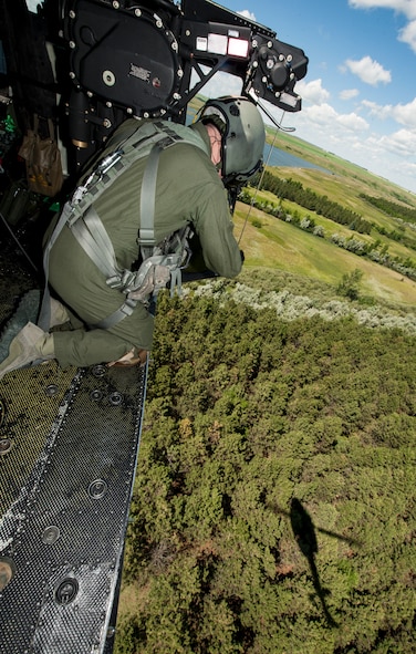 Staff Sgt. Nicholas Estrada, 54th Helicopter Squadron flight engineer, conducts search and rescue training from a UH-N1 Helicopter near Garrison, N.D., July 20, 2015. During the training, Estrada and the helicopter’s crew had to locate and hoist two tactical response force members from a field near a wooded area. (U.S. Air Force photo/Senior Airman Stephanie Morris)