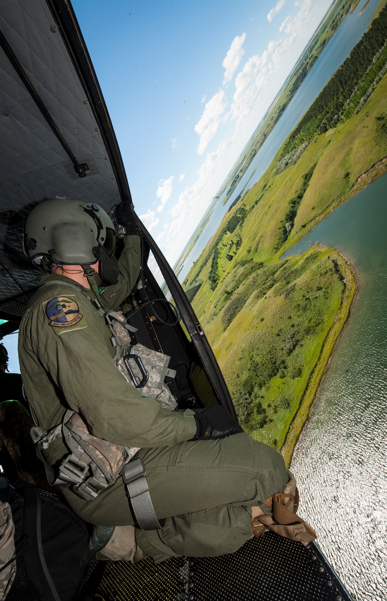 Staff Sgt. Nicholas Estrada, 54th Helicopter Squadron flight engineer, conducts search and rescue training from a UH-N1 Helicopter near Garrison, N.D., July 20, 2015. During the training, Estrada and the helicopter’s crew had to locate and hoist two tactical response force members from a field near a wooded area. (U.S. Air Force photo/Senior Airman Stephanie Morris)