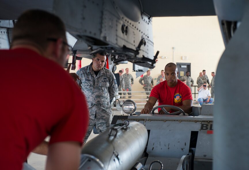 U.S. Air Force Tech Sgt. Zachary Marquis, (left), 23d Maintenance Group weapons standardization crew, evaluates Senior Airman Keelend Smith, 75th Aircraft Maintenance Unit weapons load crew member, as Smith’s team prepares to load a bomb during the load crew of the quarter competition July 17, 2015, at Moody Air Force Base, Ga. Two three-man teams from the 75th and 74th AMUs competed to determine who would be named the best load crew. (U.S. Air Force photo by Airman 1st Class Ceaira Tinsley/Released)