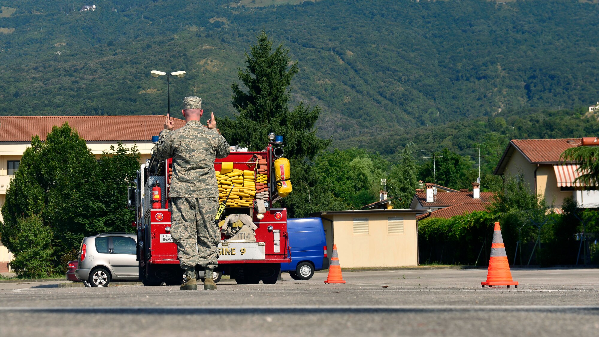 U.S. Air Force Staff Sgt. Jason Holmes, 31st Civil Engineer Squadron fire company officer, directs an Airman through a serpentine cone course, July 22, 2015, at Aviano Air Base, Italy. Airmen are trained to drive engine trucks and airport rescue fire fighting and mobile water supply vehicles. (U.S. Air Force photo by Airman 1st Class Cary Smith/Released)