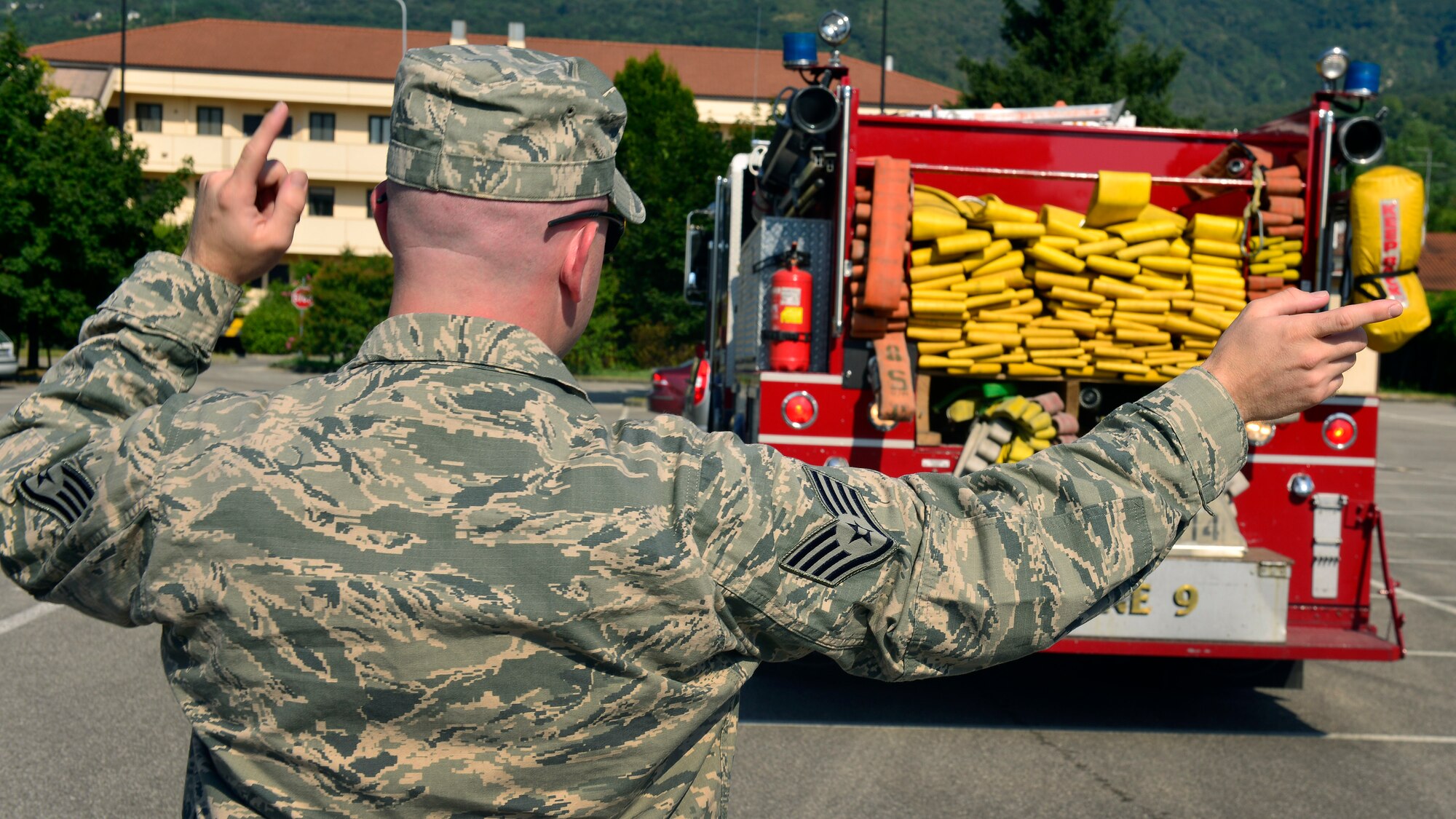 U.S. Air Force Staff Sgt. Jason Holmes, 31st Civil Engineer Squadron fire company officer, directs an Airman through a serpentine cone course, July 22, 2015, at Aviano Air Base, Italy. Airmen are trained to drive engine trucks and airport rescue fire fighting and mobile water supply vehicles. (U.S. Air Force photo by Airman 1st Class Cary Smith/Released)