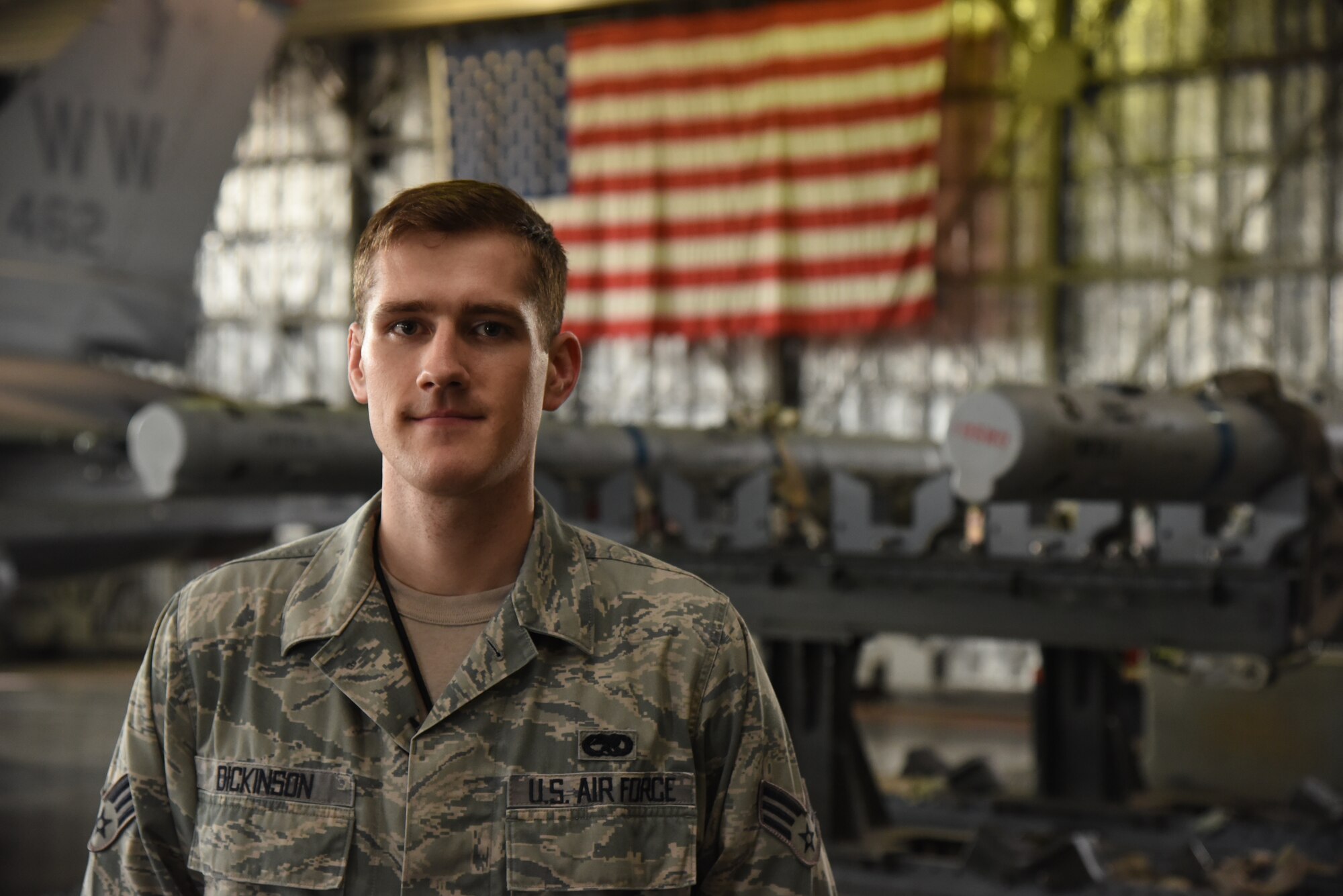 U.S. Air Force Senior Airman Robert Dickinson, 35th Maintenance Group squadron load crew member, poses in front of armaments at Misawa Air Base, Japan, July 21, 2015. Dickinson’s responsibilities include instructing new Airmen on how to load weapons efficiently and ensuring experienced load crews uphold standards. (U.S. Air Force photo by Senior Airman Patrick S. Ciccarone/Released)
