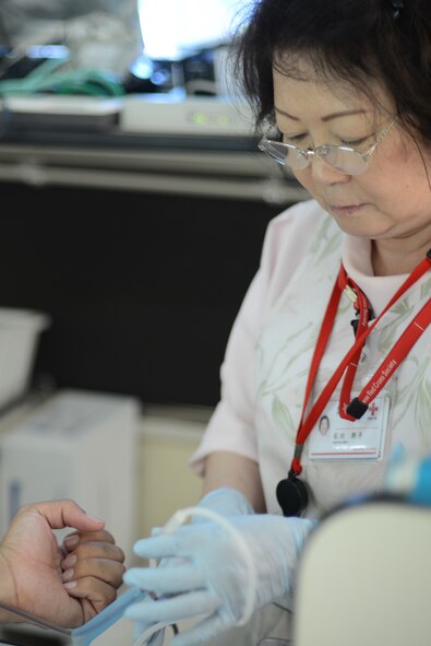 A nurse with the Japanese Red Cross Society collects blood donations from a U.S. Airman and members of the Japan Air Self-Defense Force at Yokota Air Base, Japan, July 21, 2015. Airmen and members of the Japan Air Self-Defense Force volunteered to donate blood during the event. (U.S. Air Force photo by Airman 1st Class David C. Danford/Released)