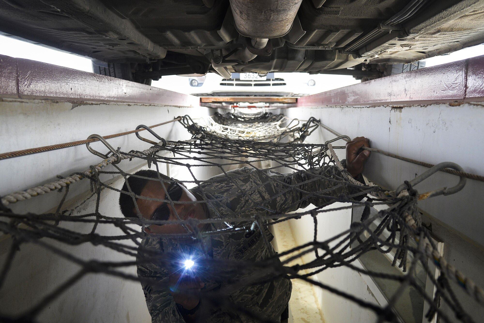 Senior Airman Alema searches the bottom of a vehicle for contraband and explosives at an undisclosed location in Southwest Asia July 13, 2015. Airman Alema is a security forces member assigned to the 380th Expeditionary Security Forces Squadron, vehicle search area. (U.S. Air Force photo/Tech. Sgt. Christopher Boitz)
