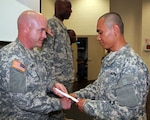 Army Chief Warrant Officer John Runyan, GED Plus company commander, awards a GED diploma to Army Pvt. Saw Blut at Camp Robinson, Ark., June 21, 2011. Blut enlisted in the Michigan Army National Guard this spring and reported to basic military training just a few days later.