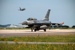 KUNSAN AIR BASE, Republic of Korea (July 16, 2015) - A 35th Fighter Squadron F-16 Fighting Falcon taxis on the Kunsan Air Base runway as an 80th Fighter Squadron F-16 Fighting Falcon takes off during Exercise Buddy Wing 15-4.  The five-day quarterly operational readiness exercise enhanced strategic capabilities at Kunsan by generating combat airpower in a simulated chemical, biological, radiological, nuclear and high-yield explosive environment. 