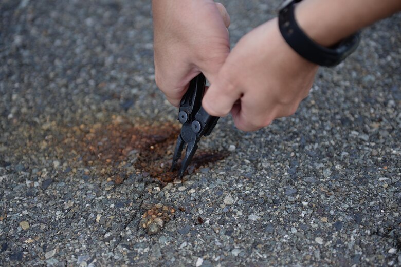U.S. Air Force Capt. Clark Morgan, 36th Mobility Response Squadron contingency engineer, plies corroded metal debris from airfield pavement July 20, 2015, Wake Island Airfield. A team with the 36th CRG at Andersen Air Force Base, Guam, deployed to the atoll to assist in airfield storm recovery efforts, and surveyed the runway to ensure adequate flightline safety. (U.S. Air Force photo by Senior Airman Alexander W. Riedel/Released)
