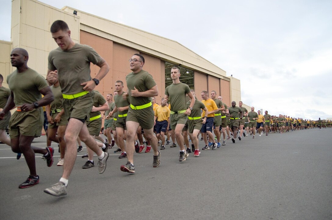 The Marines and Sailors of Marine Aviation Logistics Squadron 24, run together as a squadron out of the parking lot in front of Hangar 375, July 22, 2015. The “Warriors” conducted morning physical training with a formation run, calling cadence. (U.S. Marine Corps photo by Kristen Wong/Released)