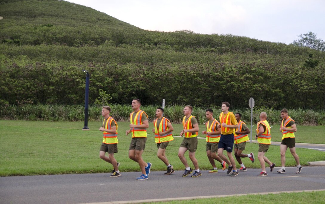The Marines and Sailors assigned as "road guards" to ensure safety during the squadron run for Marine Aviation Logistics Squadron 24 run ahead of the formation on Mokapu Road, July 22, 2015. The “Warriors” conducted morning physical training with a formation run, calling cadence. (U.S. Marine Corps photo by Kristen Wong/Released)