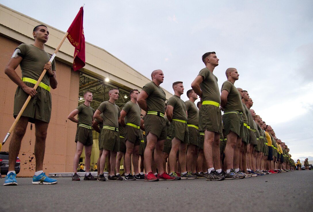 The Marines and Sailors of Marine Aviation Logistics Squadron 24, stand at parade rest before engaging in a squadron run in front of Hangar 375, July 22, 2015. Lance Cpl. Jonathan Giner (left), an aviation technician calibrator with MALS-24, and an El Paso, Texas native, holds the unit guidon. The “Warriors” conducted morning physical training with a formation run, calling cadence. (U.S. Marine Corps photo by Kristen Wong/Released)