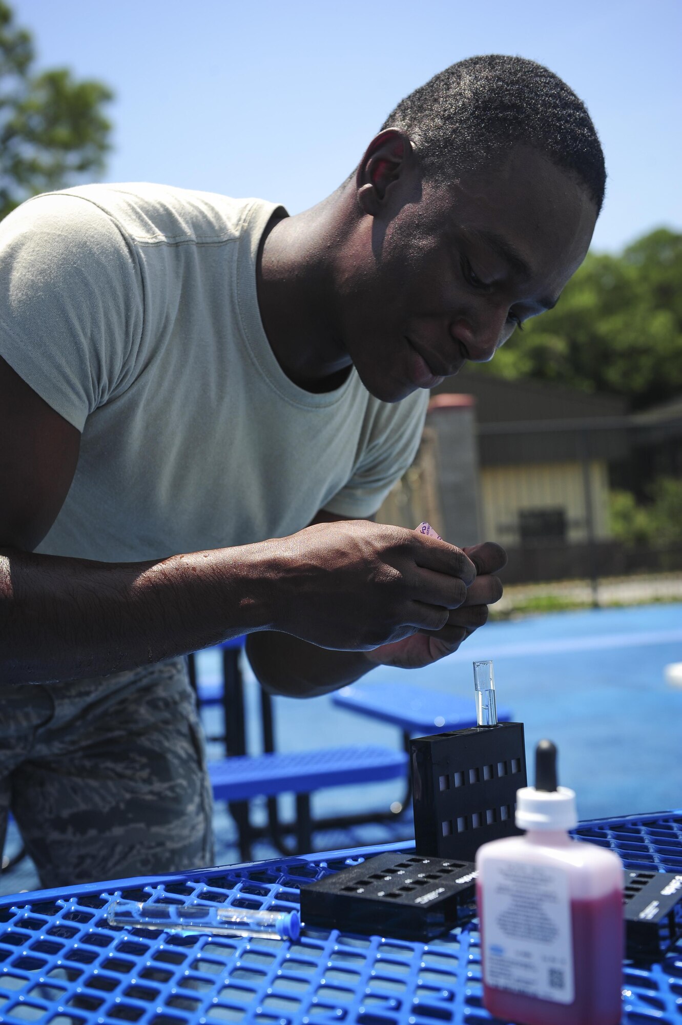 Airman 1st Class Joseph Brown, 1st Special Operations Medical Support Squadron bioenvironmental engineer technician, drops a chemical tablet into a test tube of pool water at the Aquatic Center on Hurlburt Field, Fla., July 22, 2015. The chemical tablet reacts in the water and changes color depending on the amount of  chlorine present. (U.S. Air Force photo/Senior Airman Meagan Schutter)