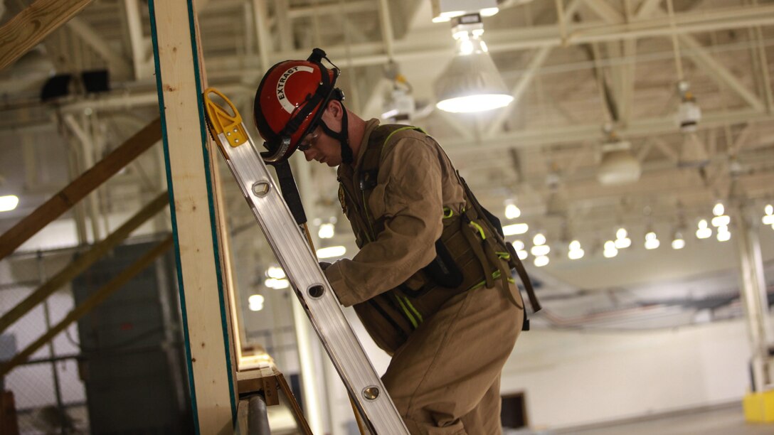 Corporal Aaron Cowley, a Marine with the Search and Extraction Platoon, climbs a ladder to breach a window during Exercise Scarlet Response 2015 at Guardian Centers in Perry, Georgia, July 21.  Securing a ladder properly and breaching windows were a couple of the techniques learned during the forcible entry scenarios. 