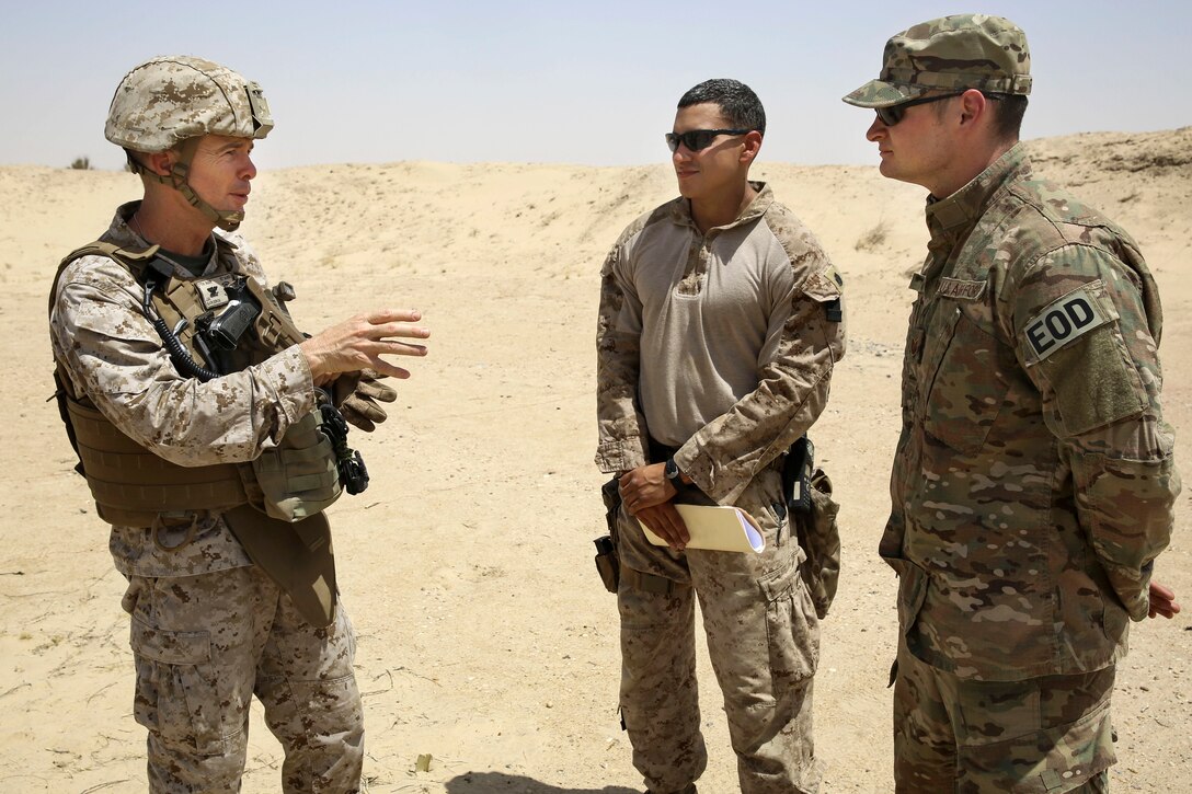 U.S. Marine Corps Col. Jay Bargeron, left, commander of Special-Purpose Marine Air-Ground Task Force-Crisis Response-Central Command, speaks with U.S. Marine Corps Staff Sgt. Joshua Martinez, center, and U.S. Air Force Tech. Sgt. Johnathan Finn, right, during a demolition range in Southwest Asia, July 17, 2015. Finn is an explosive ordnance technician assigned to the 332nd Expeditionary Civil Engineering Squadron.