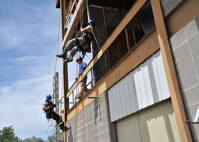 Firefighters Staff Sgt. Brandin McGovern, 120th Civil Engineer Squadron, Montana Air National Guard, left, and Senior Airman Hector Guemarez Colon, 341st CES, Malmstrom Air Force Base, rappel down the tower at the City of Great Falls Fire Training Center July 22, 2015, during the Rescue Technician One advanced rescue course in Great Falls, Mont. Staff Sgt. Adam McCarty, a rescue instructor from the Goodfellow Air Force Base, Texas, supervises their performance. The 15-day course expands the knowledge of Air Force firefighters and also includes confined space rescue training. (U.S. Air Force photo/ John Turner)