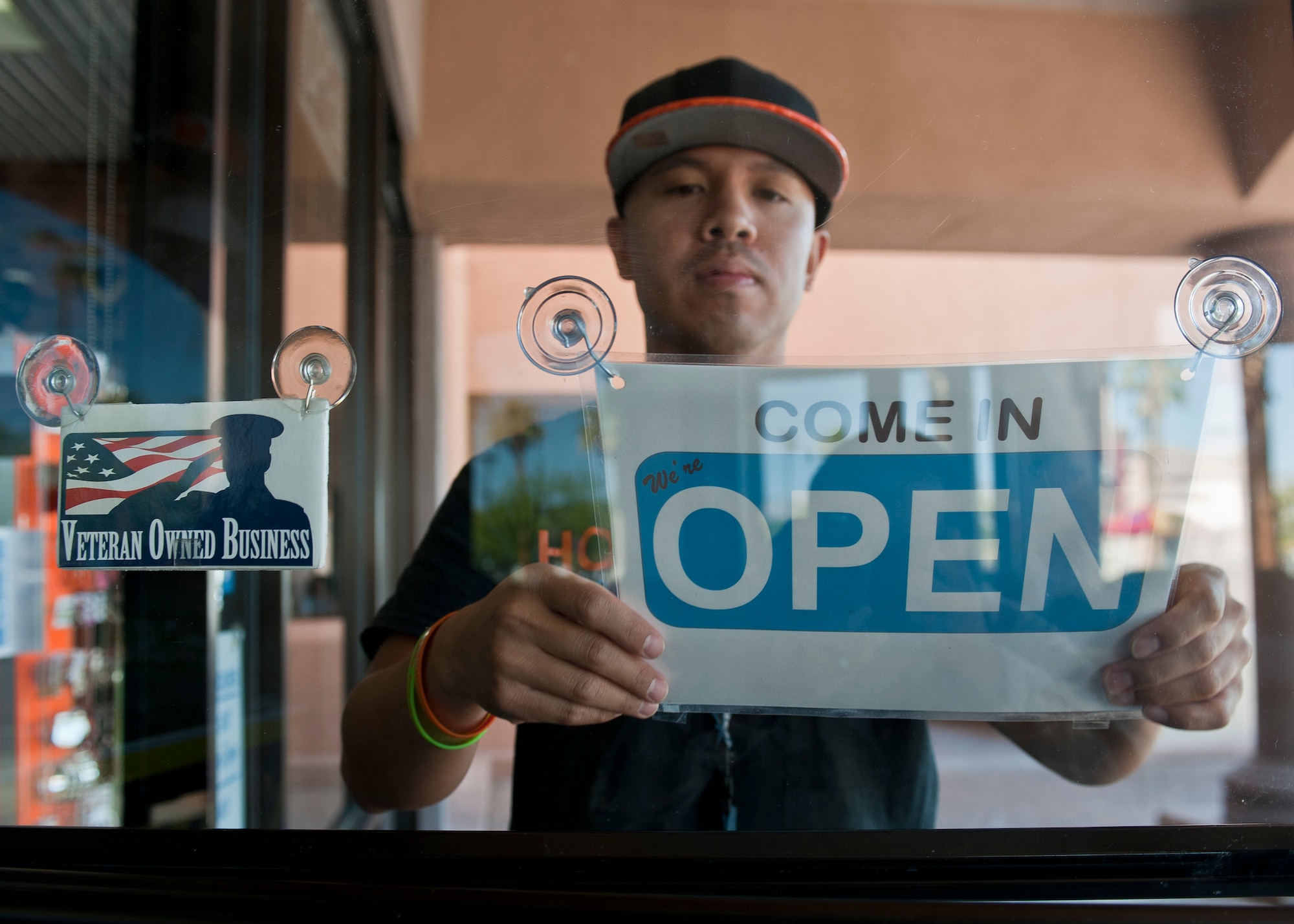 Retired Tech. Sgt. Alfredo Sibucao Jr. flips the open sign to his retail store in Las Vegas, June 22, 2015. Sibucao retired from the Air Force in 2014 and now owns and operates a small business in Las Vegas. (U.S. Air Force photo by Staff Sgt. Siuta B. Ika)