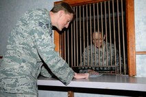 Senior Airman Benjermin Ryan, 22nd Comptroller Squadron financial management technician, hands a form to Master Sgt. Tonya Carey, 22nd CPTS quality assurance manager, for processing, July 23, 2015, at McConnell Air Force Base, Kan. “The cage” acts as a transition point to collect money for the government treasury. (U.S. Air Force photo by Airman 1st Class Christopher Thornbury)