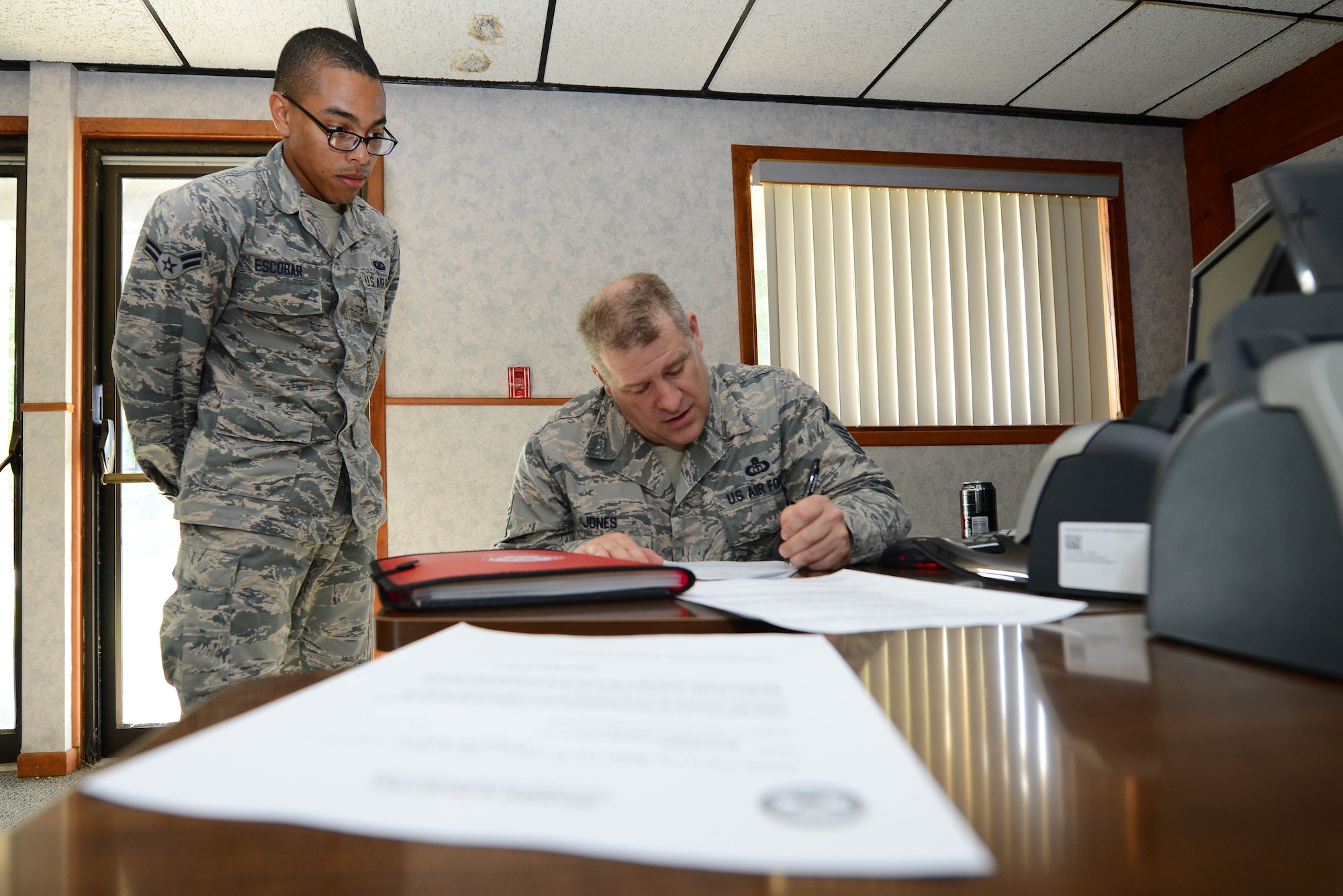Airman 1st Class James Escobar, 22nd Comptroller Squadron financial management technician, assists Master Sgt. Brad Jones, 22nd Operations Support Squadron weather training and mobility NCO in charge, with paperwork, July 23, 2015, at McConnell Air Force Base, Kan. Finance Airmen provide customer support to ensure Team McConnell is taken care of financially. (U.S. Air Force photo by Airman 1st Class Christopher Thornbury) 