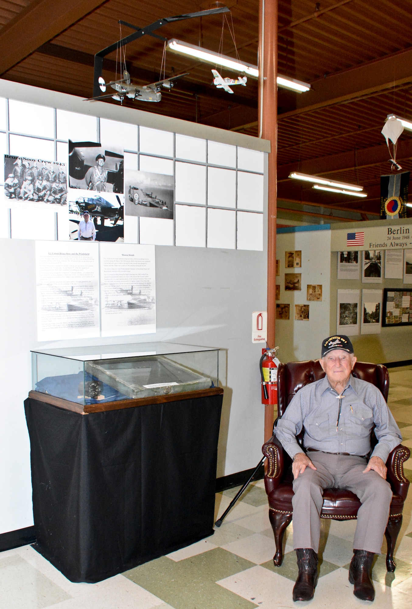 Ret. Lt. Col. Bruce Sooy sits next to his display July 15, at the Heritage Center at Travis Air Force Base, Calif. The windshield from Sooy’s B-24 Liberator that was shot down in World War II is displayed, along with photos and information about his missions. (U.S. Air Force photo by Airman 1st Class Amber Carter)