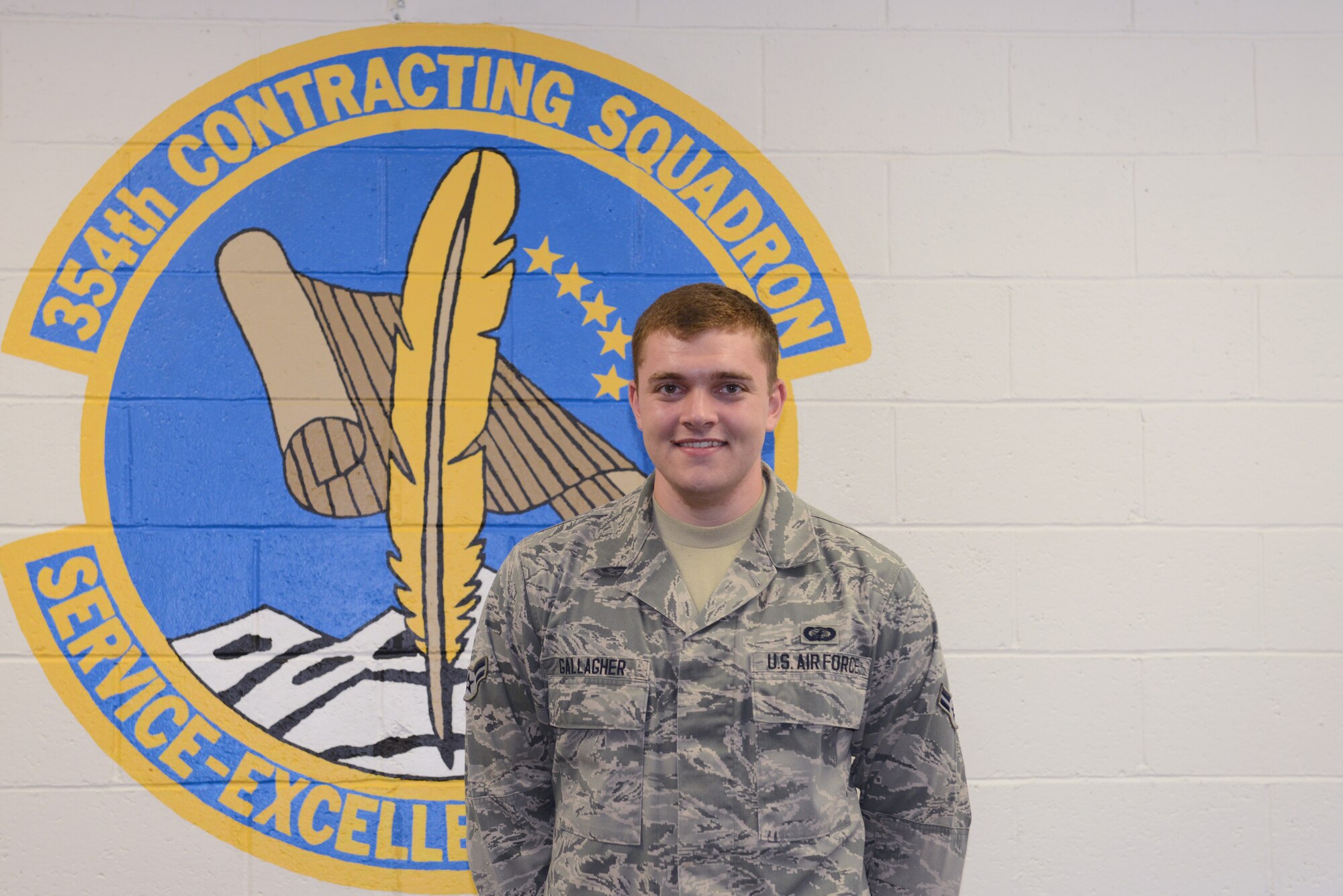 U.S. Air Force Airman 1st Class Christopher Gallagher, a 354th Contracting Squadron coordinator for the Government Purchasing Card program, pauses for a brief photo in front of his squadron patch July 21, 2015, at Eielson Air Force Base, Alaska. Gallagher said his proudest moment as a member of the Iceman team is when he was selected for Senior Airman below-the-zone. (U.S. Air Force photo by Senior Airman Ashley Nicole Taylor/Released)