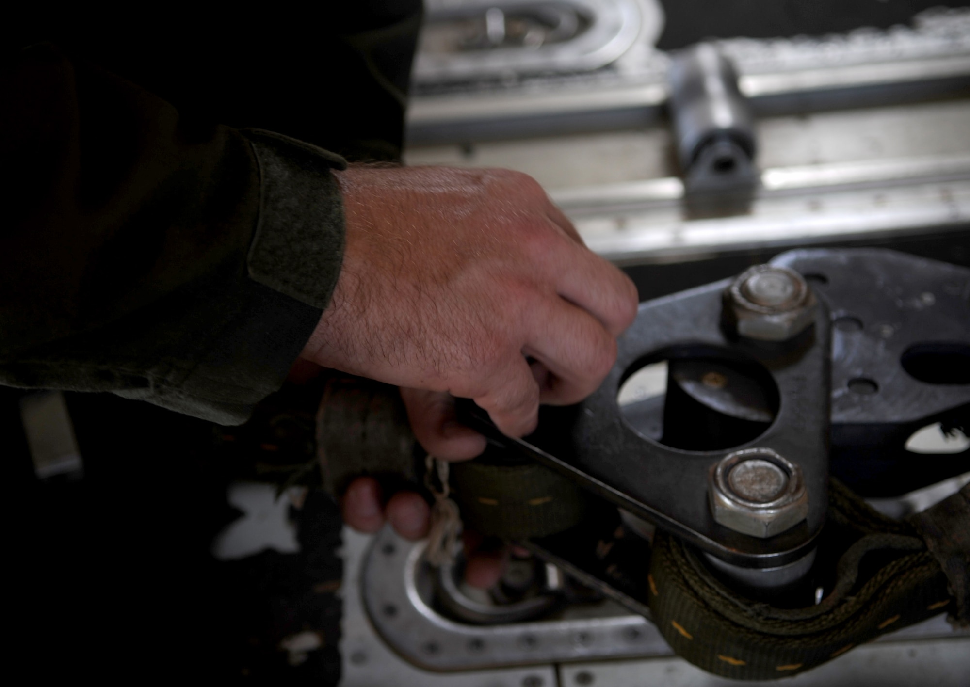 U.S. Air Force Staff Sgt. Daniel Simonsen, 39th Airlift Squadron loadmaster, tightens a bolt to a pulley system that is connected from a parachute to a heavy equipment platform, June 30, 2015, at Dyess Air Force Base, Texas. Simonsen took part in contingency training to practice airdrops to keep loadmasters and pilots mission-ready. (U.S. Air Force photo by Airman 1st Class Austin Mayfield/Released)