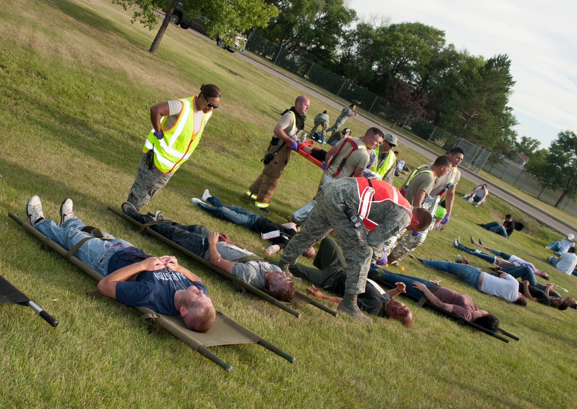 Base firefighters and emergency medical personnel load simulated aircraft accident victims onto stretchers during an exercise at Minot Air Force Base, N.D., July 22, 2015. First responders were met by approximately 40 simulated trauma victims and had to quickly treat and prioritize transportation based on the severity of their simulated injuries. (U.S. Air Force photo/Senior Airman Stephanie Morris)