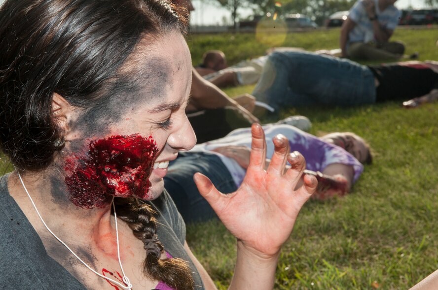 Airman 1st Class Aleah Meade, 5th Munitions Squadron storage crew member, grimaces from a mock burn wound during an exercise at Minot Air Force Base, N.D., July 22, 2015. Meade was one of approximately 40 volunteers who portrayed trauma victims during the exercise. (U.S. Air Force photo/Senior Airman Stephanie Morris)