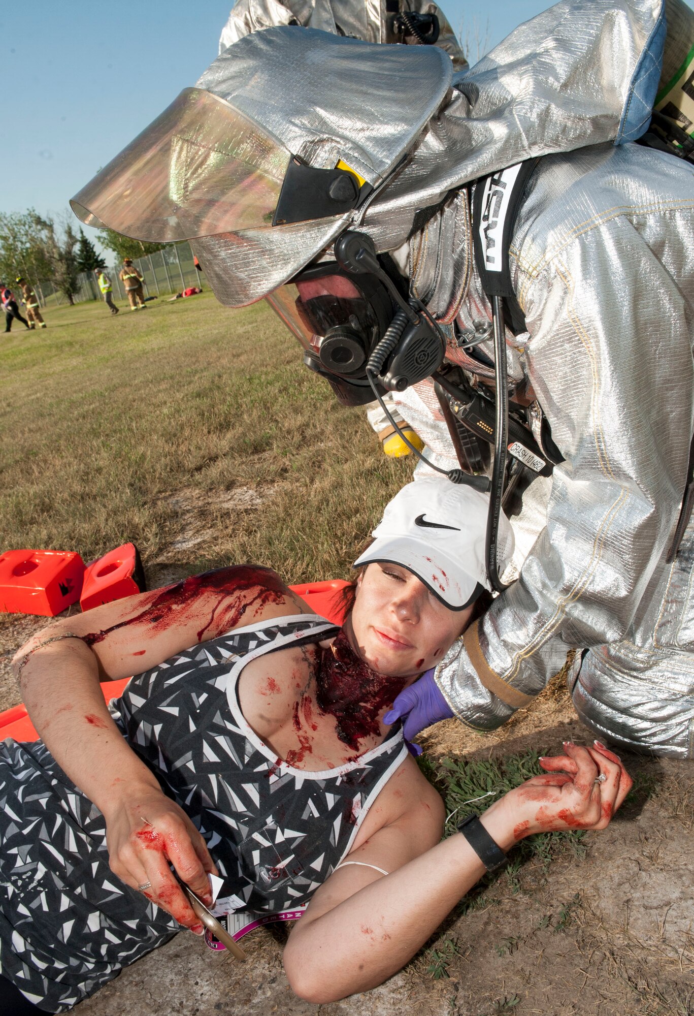 Staff Sgt. Symphony Leyk, 5th Security Forces Squadron alarm monitor, is loaded onto a back board by 5th Civil Engineer Squadron firefighters during an exercise at Minot Air Force Base, N.D., July 22, 2015. Leyk had a simulated neck wound which emergency responders had to identify and treat during the exercise. (U.S. Air Force photo/Senior Airman Stephanie Morris)