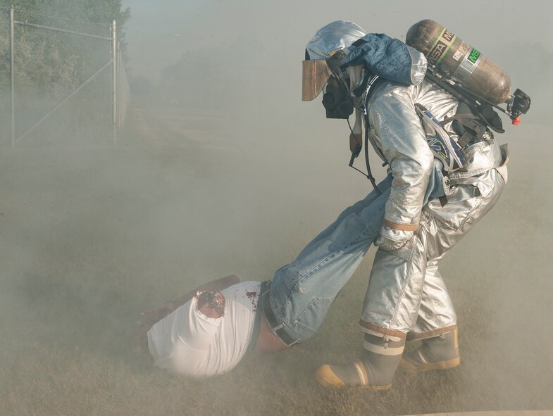 A firefighter from the 5th Civil Engineer Squadron, pulls an Airman posing as a burn victim away from a simulated fire at Minot Air Force Base, N.D., July 22, 2015. Firefighters were the first on scene for a mass casualty exercise at the 5th Medical Group. (U.S. Air Force photo/Senior Airman Stephanie Morris)