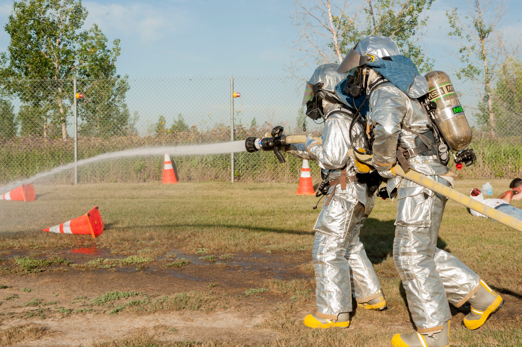 Firefighters from the 5th Civil Engineer Squadron, topple cones during an exercise at Minot Air Force Base, N.D., July 22, 2015. The cones represented fire from a simulated aircraft accident. (U.S. Air Force photo/Senior Airman Stephanie Morris)
