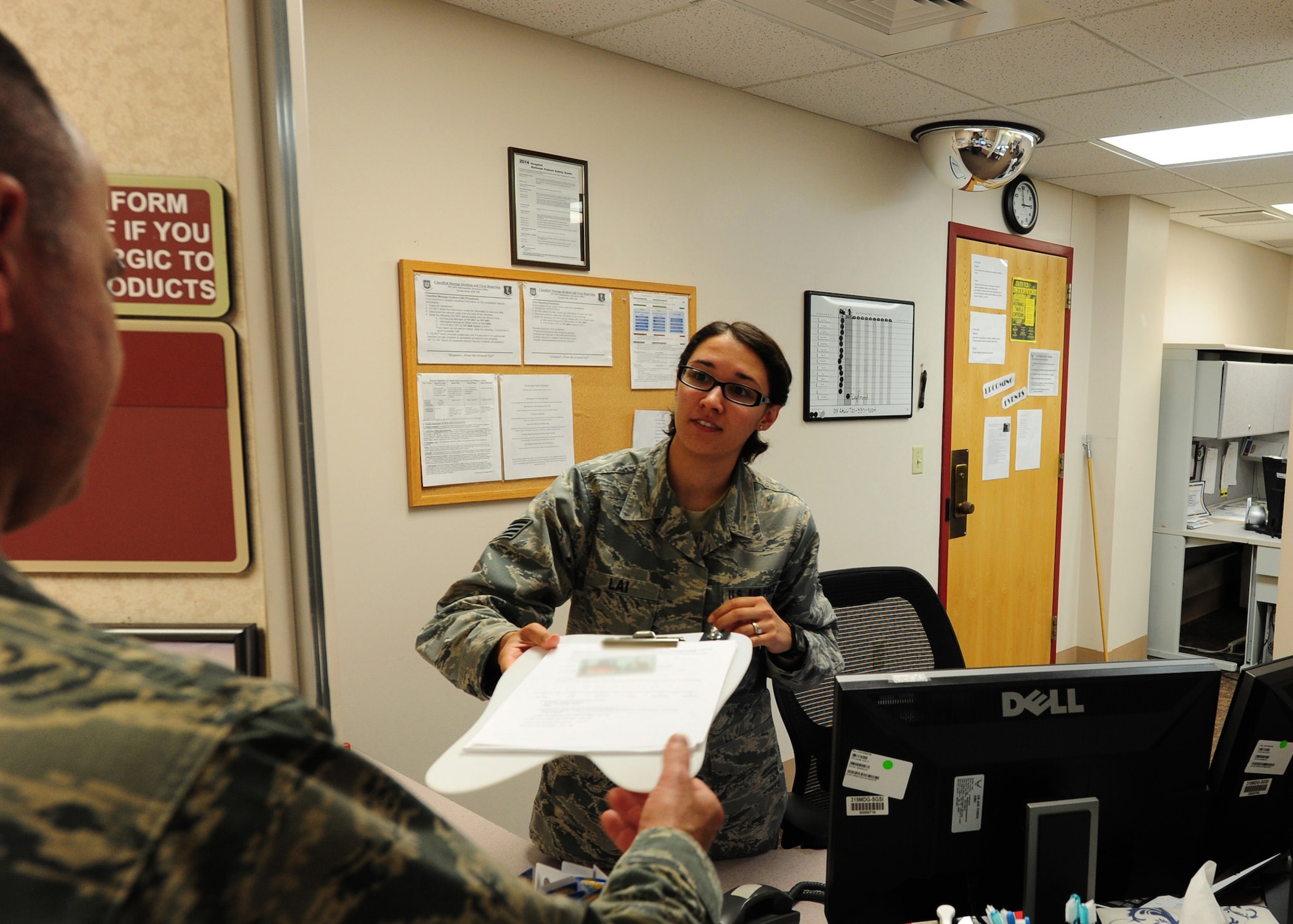 Staff Sgt. Allison Lai, 319th Medical Operations Squadron NCO-in-charge of dental support, hands paperwork to a customer July 21, 2015, at the Medical Treatment Facility on Grand Forks Air Force Base, N.D. Lai was selected as the Warrior of the Week for the fourth week of July. (U.S. Air Force photo by Airman 1st Class Ryan Sparks/released)
