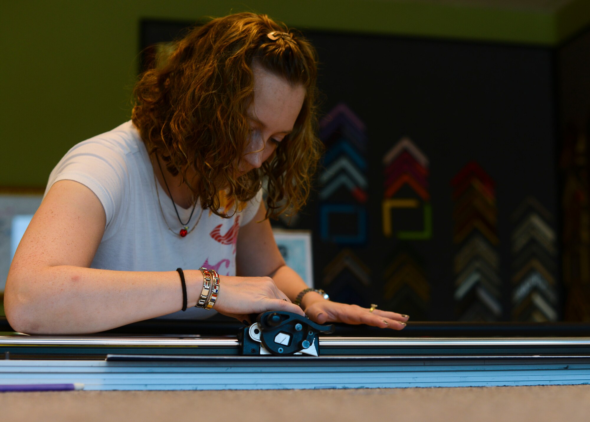 Nancy Bruno, 31st Force Support Squadron custom frame designer, cuts matte paper for a frame, July 23, 2015, at Aviano Air Base, Italy. Customers work with Bruno to create individualized frames for photos or artwork. (U.S. Air Force photo by Senior Airman Austin Harvill/Released)