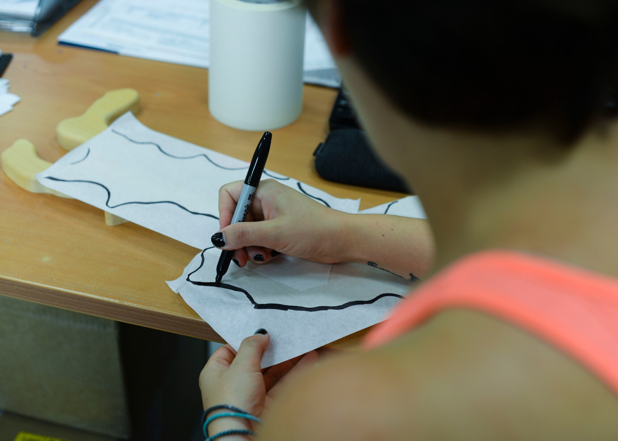 Victoria Stefos, 31st Force Support Squadron engraver, outlines a test sheet before placing a wooden slab down for engraving, July 21, 2015, at Aviano Air Base, Italy. In addition to engraving, customers can purchase frames and print their own photos at the store. (U.S. Air Force photo by Senior Airman Austin Harvill/Released)
