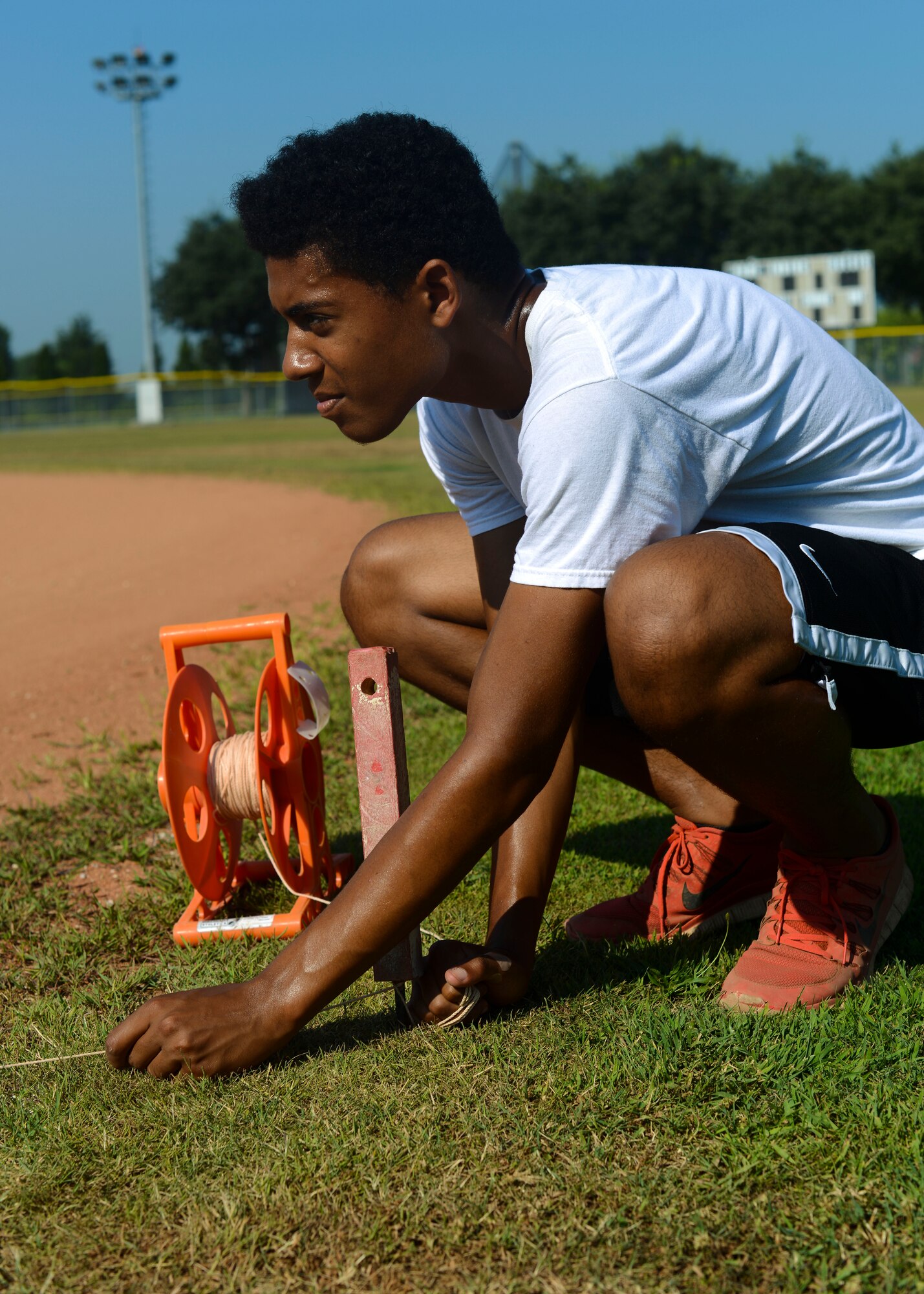Jaylen Esposito, Summer Hire Program employee and of U.S. Air Force Master Sgt. Justin Esposito, sets a line before chalking a baseball field, July 20, 2015, at Aviano Air Base, Italy. The program allows Aviano teens to work a full-time job and learn skills such as time management and personal responsibility. (U.S. Air Force photo by Senior Airman Austin Harvill/Released)