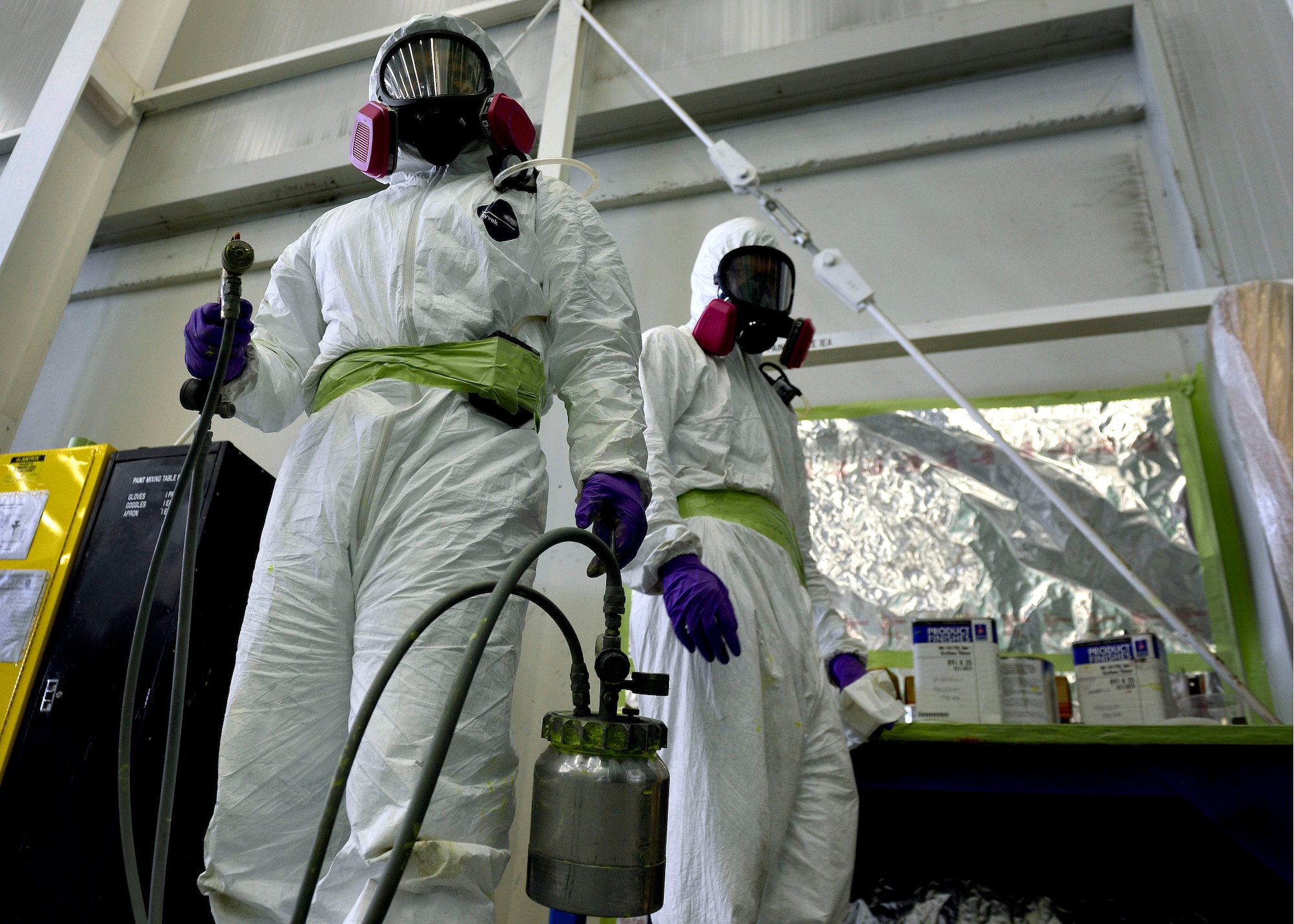(From left) U.S. Air Force Tech. Sgt. Benjamin Jimenez, 31st Maintenance Squadron NCO in charge of corrosion control, and Airman Justin King, 31 MXS aircraft structural maintenance apprentice, prepare paint to spray on an F-16 Fighting Falcon, July 16, 2015, at Aviano Air Base, Italy. The aircraft body is sprayed with a chemical coat of primer and then a top coat every four to six years to prevent corrosion from occurring. (U.S. Air Force photo by Airman 1st Class Cary Smith/Released)