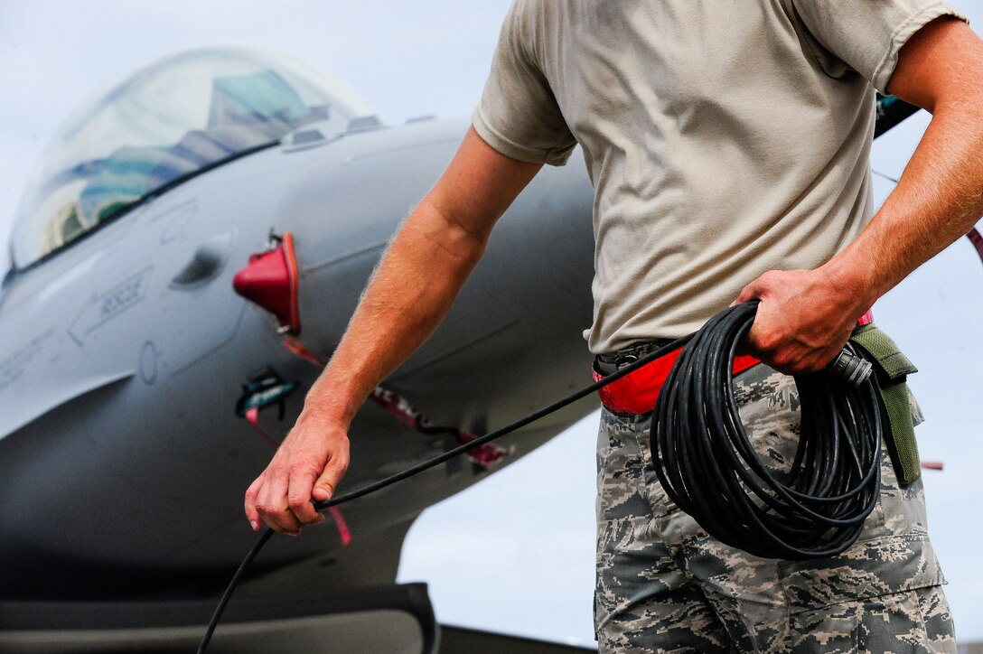 U.S. Air Force Master Sgt. David Custer, Vermont Air National Guard’s 158th Maintenance Squadron lead crew chief, coils up a communication wire in front of a U.S. Air Force F-16 Fighting Falcon on Kadena Air Base, Japan, July 22, 2015. The F-16 is a compact, multi-role fighter aircraft. The 158th ANG Fighter Wing is temporarily deployed to Kadena to provide a theater security package throughout the Indo-Asia-Pacific region. (U.S. Air Force photo by Airman 1st Class John Linzmeier) 