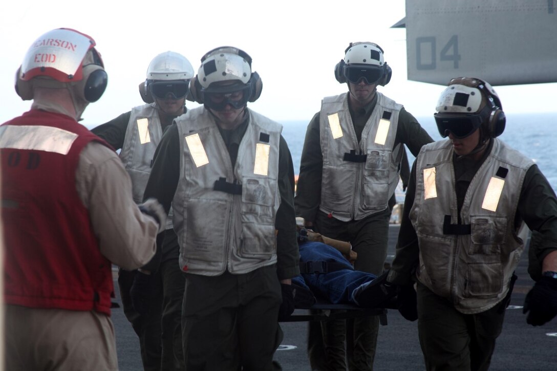 INDIAN OCEAN (July 20, 2015) U.S. Marine Staff Sgt. Peter Pearson, left, prepares to search a simulated casualty for explosives as combat cargo Marines carry the injured aboard the amphibious assault ship USS Essex (LHD 2). Pearson is an explosives ordnance disposal technician with Combat Logistics Battalion 15, 15th Marine Expeditionary Unit.  Combat cargo Marines offloaded simulated casualties from an aircraft and brought them to the Essex’s medical staff for further care. Elements of the 15th MEU, based out of Camp Pendleton, California, and embarked aboard the Essex, are conducting naval operations in the 6th Fleet area of operations in support of U.S. national security interests in Europe and Africa. (U.S. Marine Corps photo by Staff Sgt. Miguel Carrasco/Released)