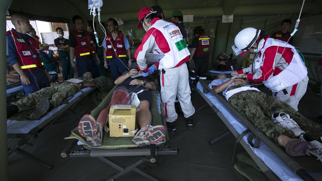 Members of the Japan Ground Self Defense Force and Japan Disaster Medical Assistance Team assist a role player off an ambulance July 23, during the Churashima Rescue Exercise on Camp Naha, Okinawa, Japan. The annual exercise hosted by the 15th Brigade, Western Army, Japan Ground Self Defense Force, trains emergency responders for a swift reaction to the disaster effects of a trench-type earthquake. “In close cooperation with prefectural disaster response organizations, both civilian and defense, we practiced how information is shared, where we need to improve, and what we can accomplish next time more fully,” said Japan Ground Self Defense Force Lieutenant Colonel Naruhito Seo, 15th Brigade Headquarters.