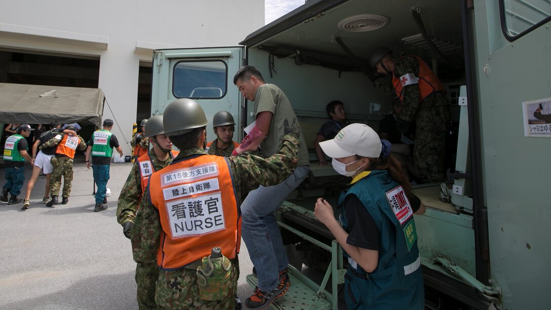 Members of the Japan Ground Self Defense Force and Japan Disaster Medical Assistance Team assist a role player off an ambulance July 23, during the Churashima Rescue Exercise on Camp Naha, Okinawa, Japan. The annual exercise hosted by the 15th Brigade, Western Army, Japan Ground Self Defense Force, trains emergency responders for a swift reaction to the disaster effects of a trench-type earthquake. “In close cooperation with prefectural disaster response organizations, both civilian and defense, we practiced how information is shared, where we need to improve, and what we can accomplish next time more fully,” said Japan Ground Self Defense Force Lieutenant Colonel Naruhito Seo, 15th Brigade Headquarters. 