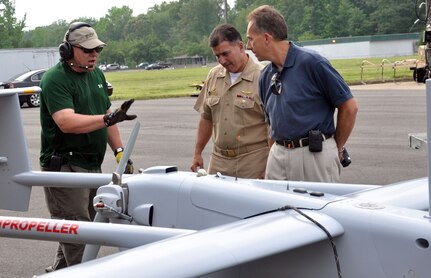 Donn Rushing, left, crew chief for the Unmanned Aerial Systems Test Directorate, briefs Capt. Pete Nette, center, commanding officer of Naval Support Activity South Potomac, and Nelson Mills, right, senior engineer at the Naval Surface Warfare Center Dahlgren Division, about the Aerostar UAS in the foreground during testing May 21. The planning phase of the test required extensive coordination with between Dahlgren-based commands, Naval Air Systems Command and the FAA.