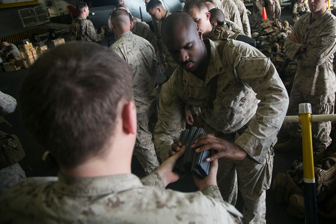 INDIAN OCEAN (July 21, 2015) U.S. Marines with Lima Company, Battalion Landing Team 3rd Battalion, 1st Marine Regiment, 15th Marine Expeditionary Unit (MEU), receive magazines and ammo during a quick reaction force rehearsal aboard the amphibious assault ship USS Essex (LHD 2). Elements of the 15th MEU, based out of Camp Pendleton, California, and embarked aboard the Essex, are conducting naval operations in the 6th Fleet area of operations in support of U.S. national security interests in Europe and Africa. (U.S. Marine Corps photo by Cpl. Anna Albrecht/Released)
