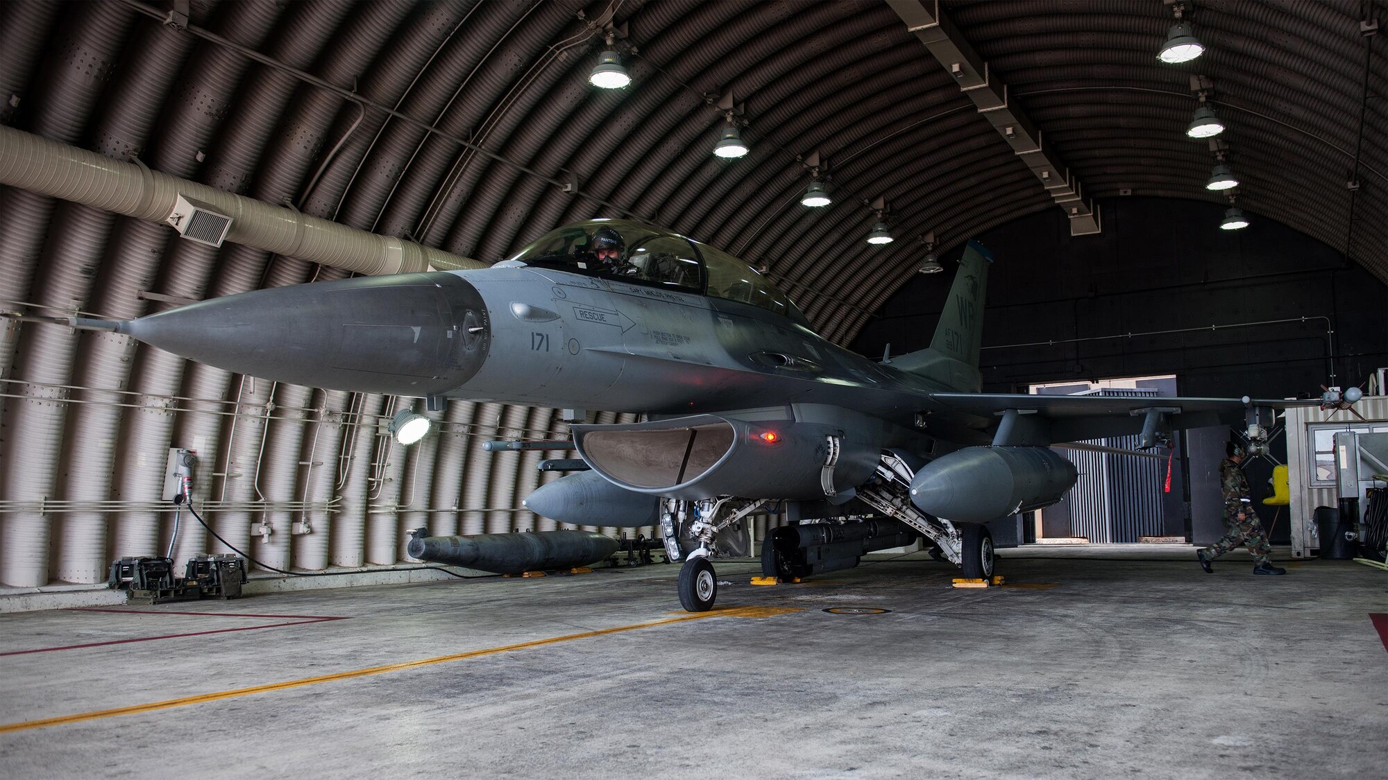 A U.S. Air Force 35th Fighter Squadron F-16 Fighting Falcon pilot prepares to taxi as U.S. Air Force Senior Airman Jeff Bryant, 35th Aircraft Maintenance Unit crew chief, conducts a pre-flight inspection during Exercise Beverly Midnight 15-4, at Kunsan Air Base, Republic of Korea, July 16, 2015. During the five-day operational readiness exercise, the Wolf Pack responded to counterattack tactics, simulated enemy attacks and generated combat airpower in a simulated chemical, biological, radiological, nuclear and high-yield explosive environment. (U.S. Air Force photo by Senior Airman Katrina Heikkinen/Released)