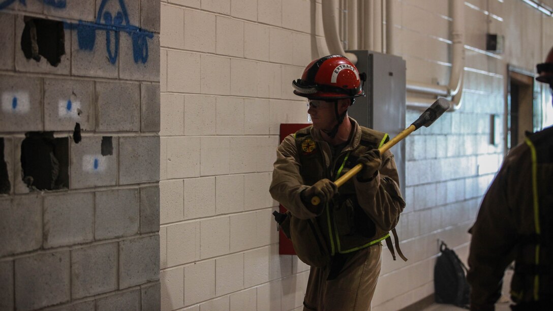 Corporal Aaron Cowley, a Marine with the Search and Extraction Platoon breaks through a cinder block wall during Exercise Scarlet Response 2015 at Guardian Centers in Perry, Georgia, July 21.  Securing a ladder properly and breaching windows were a couple of the techniques learned during the forcible entry scenarios. 