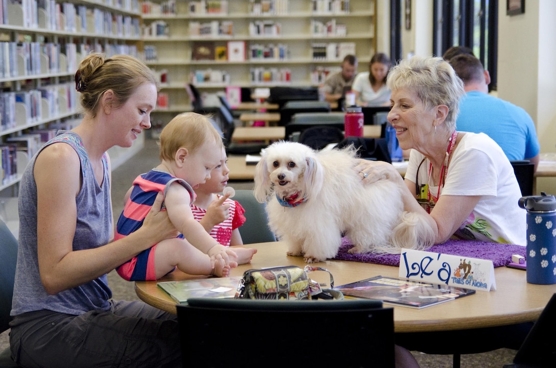 A family shares some social time with Le‘a, a Maltese/poodle mix, and her handler, during the Reading to Dogs event at the base library, July 22, 2015. Le‘a is certified with the Reading Education Assistance Dogs program from Intermountain Therapy Animals, a nonprofit organization based in Salt Lake City. Le‘a is also a therapy dog with Tails of Aloha, a local nonprofit that provides therapy dog visits to locations islandwide. The mission of Marine Corps Base Hawaii is to provide facilities, programs and services in direct support of units, individuals and families in order to enhance and sustain combat readiness for all operating forces and tenant organizations aboard MCB Hawaii. (U.S. Marine Corps photo by Kristen Wong/Released)