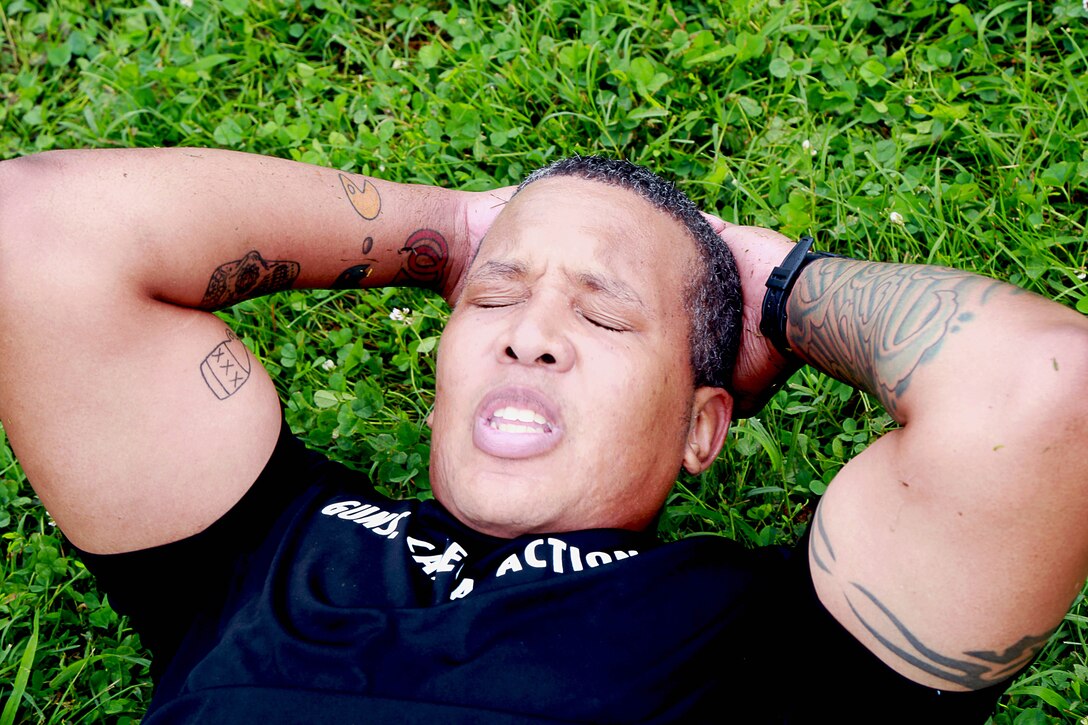 Air Force Master Sgt. Dominique Dickens participates in the sit-ups event during the 3rd annual U.S. Army Spc. Hilda I. Clayton Best Combat Camera competition on Fort Meade, Md., July 13, 2015. Dickens is assigned to 1st Combat Camera Squadron.