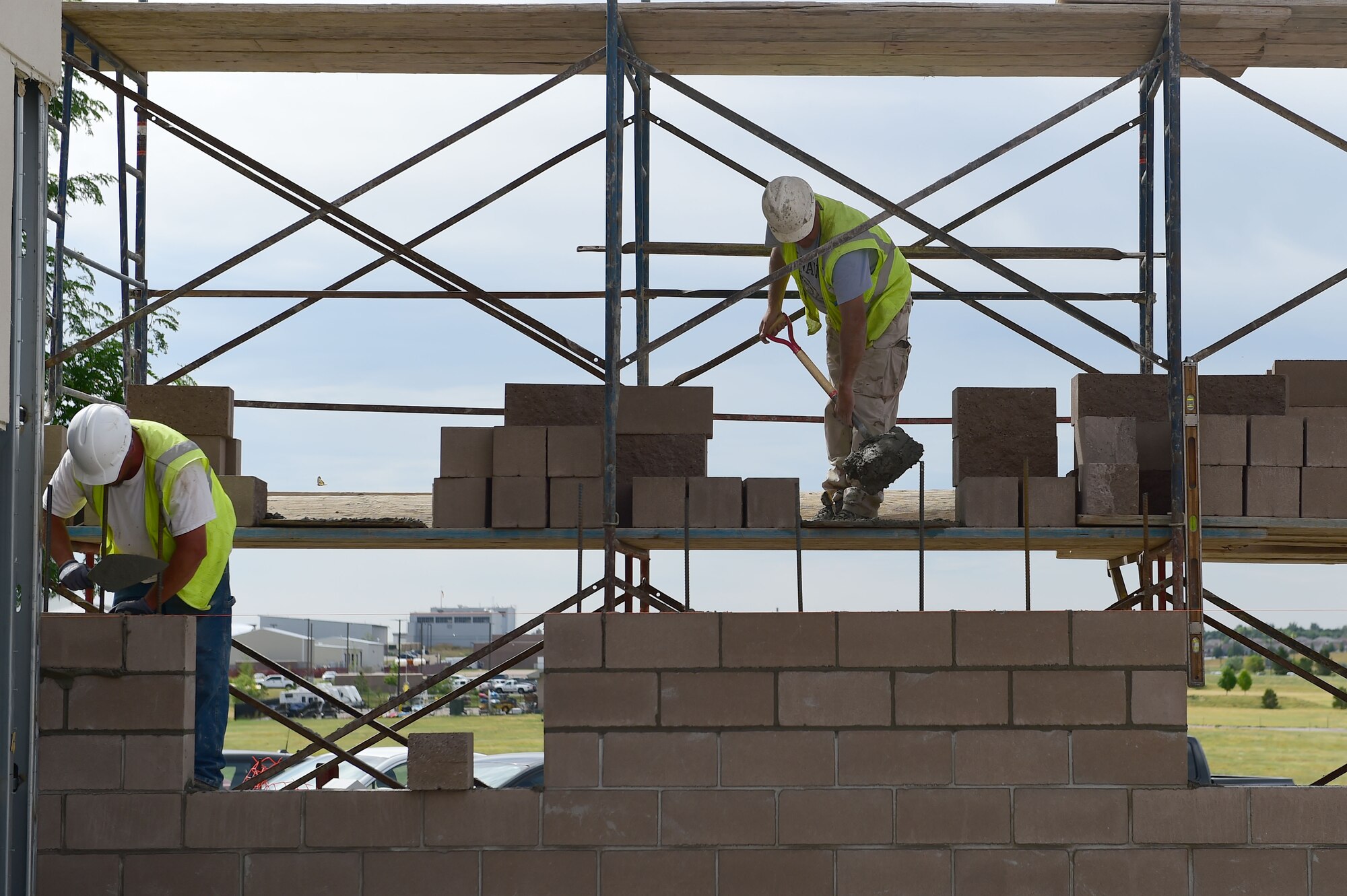 Mike Bruington and Rich Pludowski, masons with Alaric Inc., a masonry contractor, lay mortar and cinderblocks during construction on the firehouse July 24, 2015, on Buckley Air Force Base, Colo. The new renovations to the firehouse will include five new dormitories for Buckley firefighters. (U.S. Air Force photo by Airman 1st Class Luke W. Nowakowski/Released)  